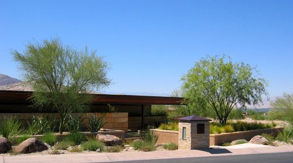 Modern desert home with minimalist landscaping under a clear blue sky.
