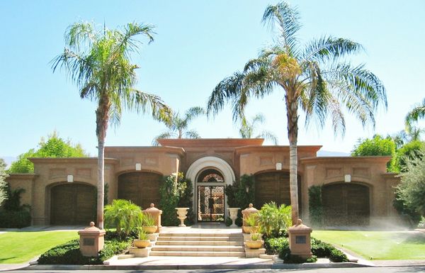 Luxurious house with palm trees and well-maintained garden.