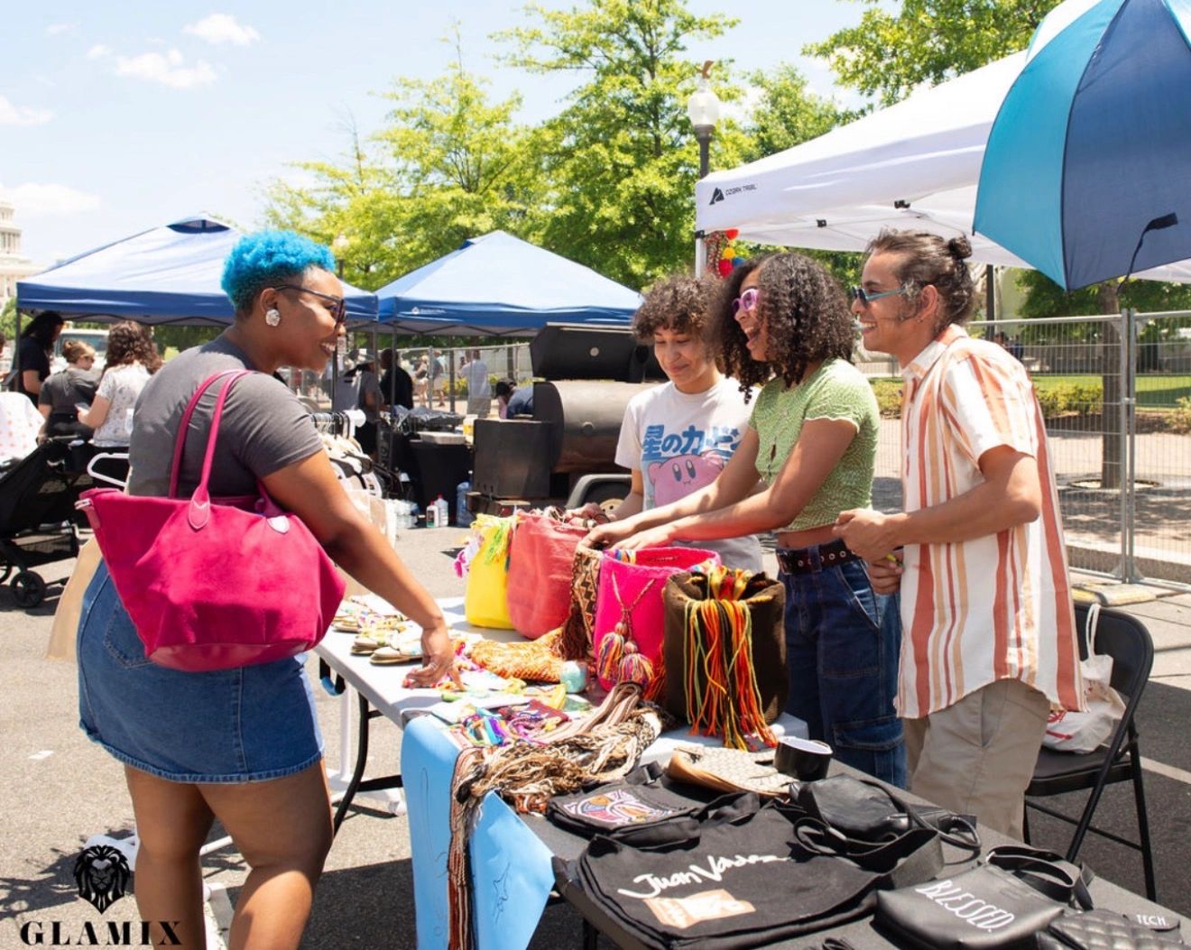 People shopping at an outdoor market stall with handmade goods.
