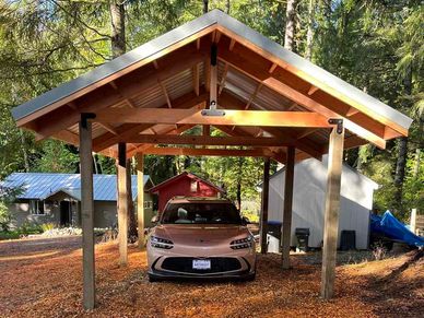 12x24 wood framed carport with gray metal roof, sheltering a new sports car from the weather.