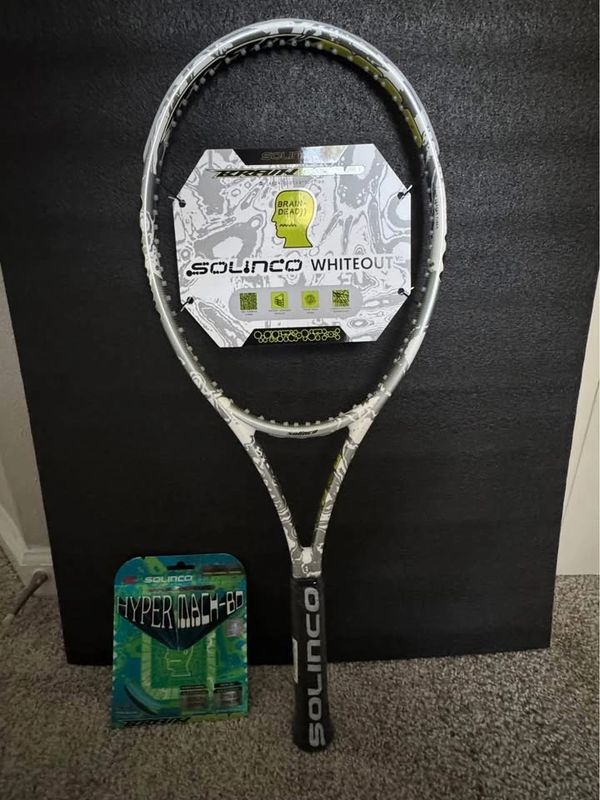 Solinco Whiteout V2 tennis racket with Hyper Mach 80 strings on a black background.