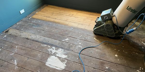 Sanding old pine floorboards in a bedroom