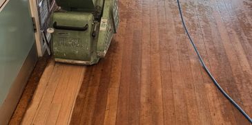 Old wooden strip floor being machine sanded.