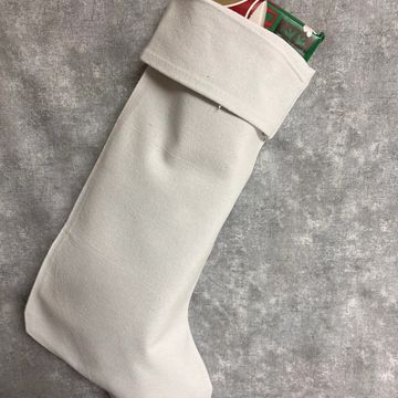 a white stocking with presents inside on a grey and white marble background. 