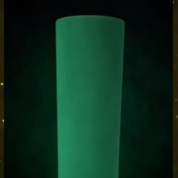 A glow-in-the-dark green cup on a black background. 