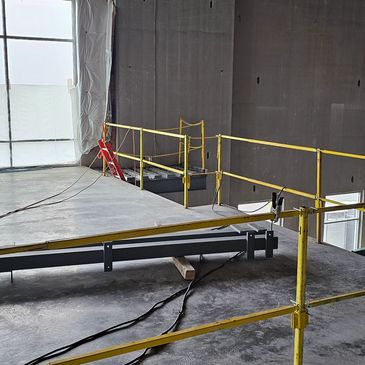 Industrial mezzanine under construction with yellow safety railings.