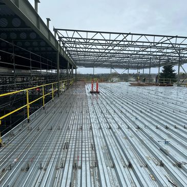 Steel framework and decking at a construction site under cloudy sky.