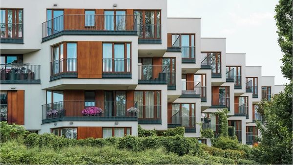 Modern apartment building with staggered balconies and wooden paneling.