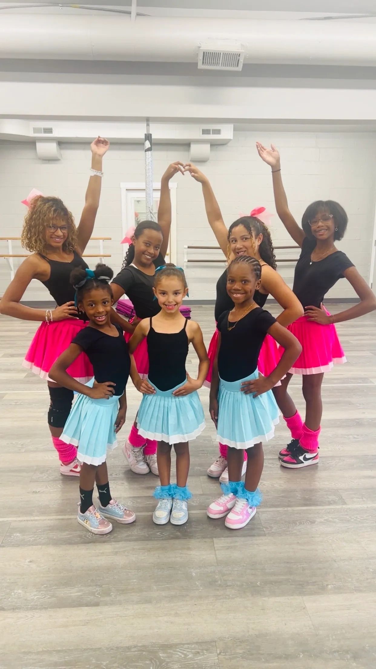 Group of young girls in colorful dance skirts posing in a studio.