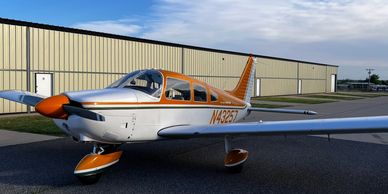 Small orange and white single-engine airplane on the ground.