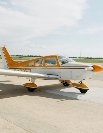 Small yellow and white single-engine airplane on tarmac.