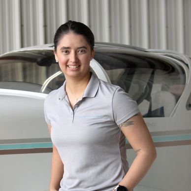 Woman standing in front of a small airplane smiling.