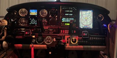 Illuminated aircraft cockpit with navigation displays and instruments.