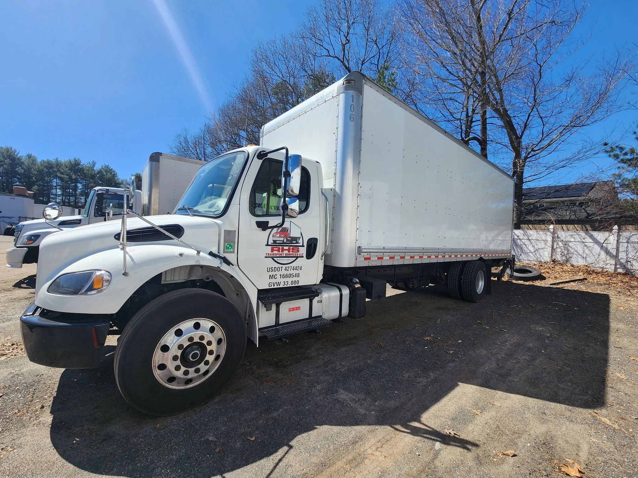 White RHS Transport Services LLC box truck parked under clear blue sky.