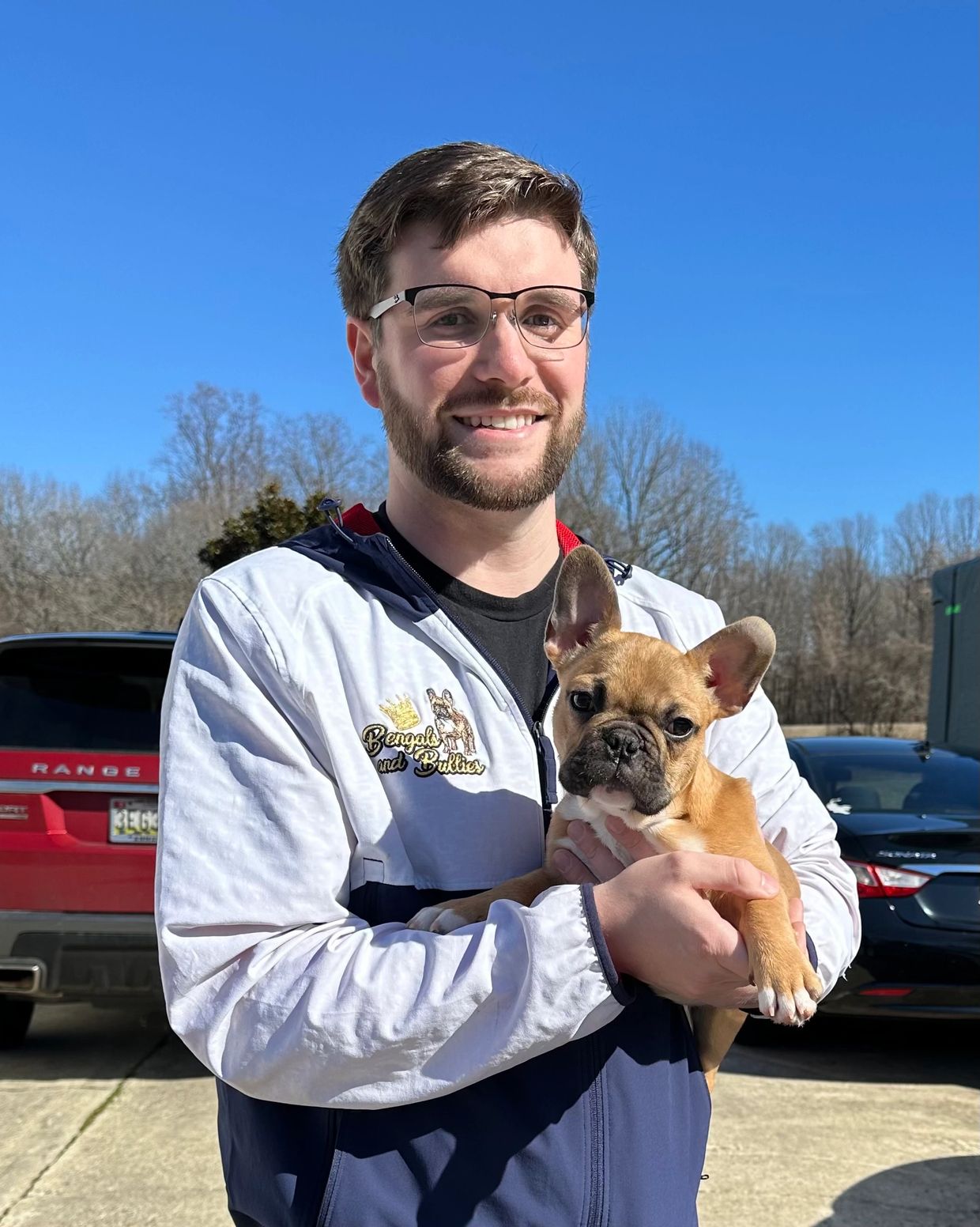 Bengals and Bullies breeder holding French Bulldog puppy outside on a sunny day.