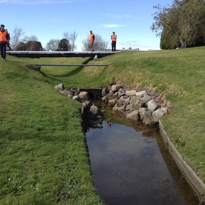 Bridge over a small creek with people walking nearby.