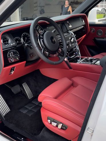Luxurious red leather interior of a Rolls-Royce Cullinan with advanced controls.