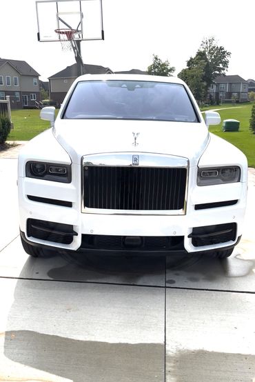 Front view of a white Rolls-Royce parked in a driveway.