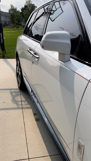 Close-up of a white Rolls-Royce car door with reflective windows and a basketball hoop reflection.
