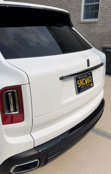 White Rolls-Royce SUV with Michigan license plate parked on driveway.