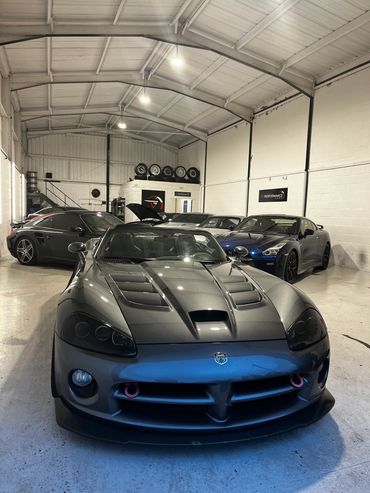 Sleek sports cars parked inside a well-lit garage with spare wheels on the wall.