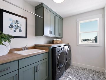 Amenities Page. Home laundry space, with window, finished in green/white, washer & dryer in black.