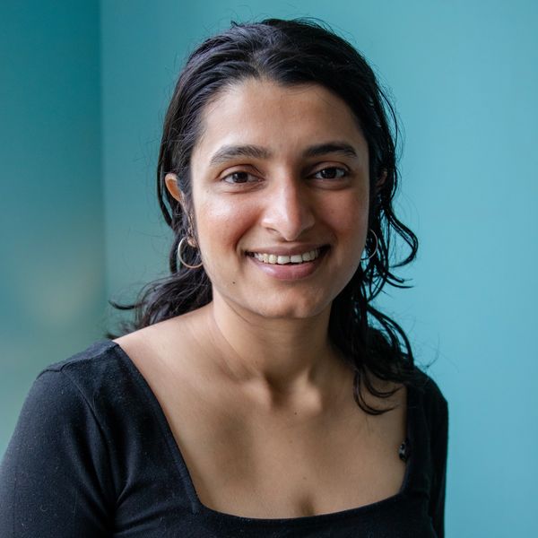 Smiling woman with dark hair against a teal background.