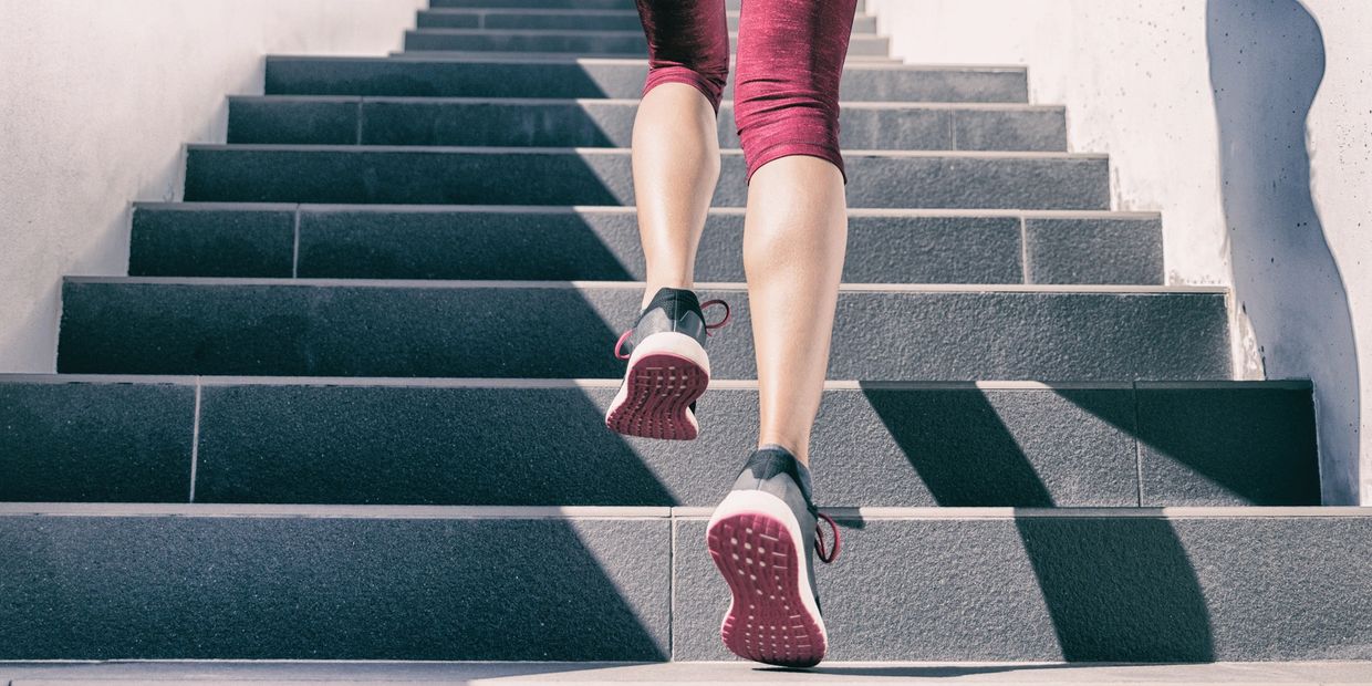Person running up outdoor stairs wearing black and pink shoes.