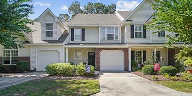 A row of modern townhomes with garages and well-maintained landscaping.
