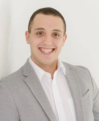 Man in gray suit smiling against a white background.