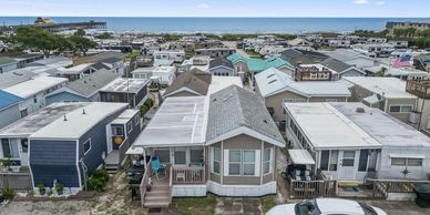 Cozy beachside mobile homes with a white car parked in front and ocean in the background.