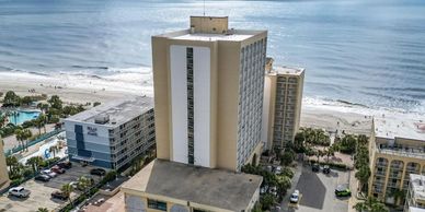 View of beachfront hotels and the ocean under a partly cloudy sky.