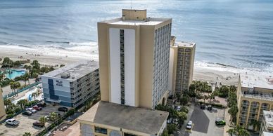 View of beachfront hotels and the ocean under a partly cloudy sky.