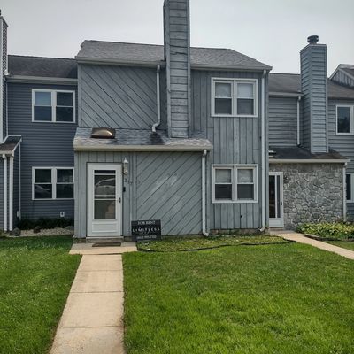 Gray townhouse with green lawn and for rent sign.