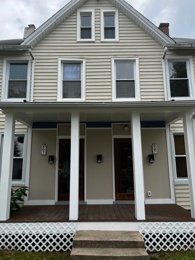 Two-story beige house with front porch and white columns.