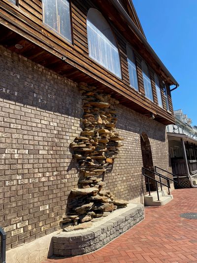 Stone sculpture embedded in a brick wall beneath windows.