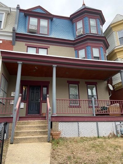 Victorian-style house with blue and beige exterior, featuring a porch and bay windows.