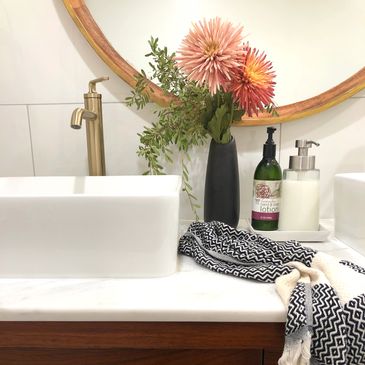 Vessel sink and silk flowers in black vase on marble topped mid-century modern dresser-turned-vanity