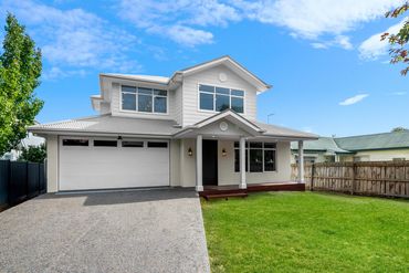 Modern two-story house with a well-maintained front lawn and a double garage.