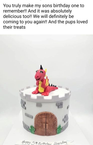 A dragon-themed birthday cake shaped like a castle with a red dragon on top.