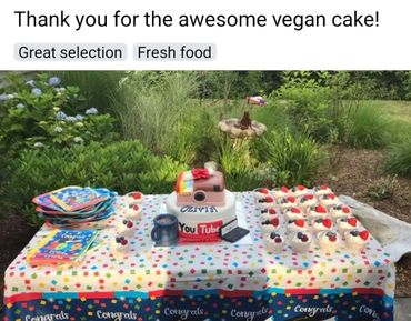 Outdoor celebration table with vegan cake, cupcakes, and colorful party plates.