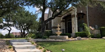 Modern house with a fountain and landscaped front yard.