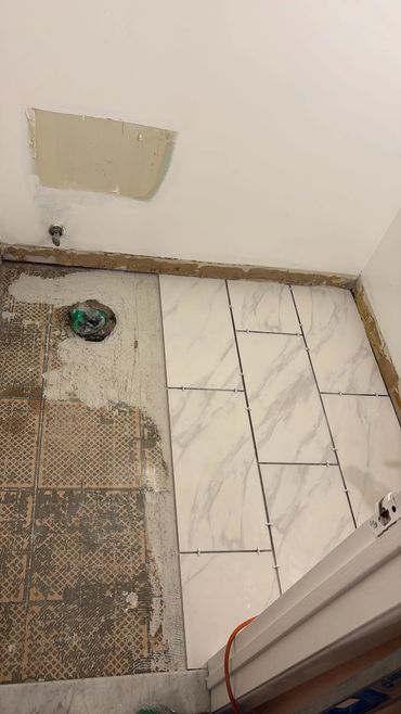 Partially tiled floor in a bathroom under renovation.