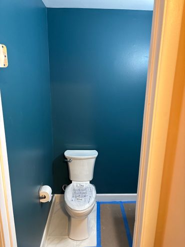 Newly painted teal bathroom with a clean white toilet.
