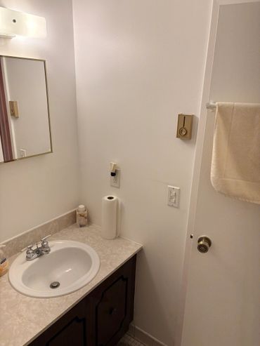 A small bathroom sink area with a mirror and towel on the door.
