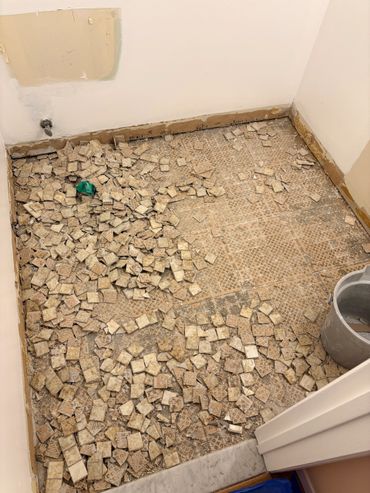 Room floor with broken tiles scattered during renovation.