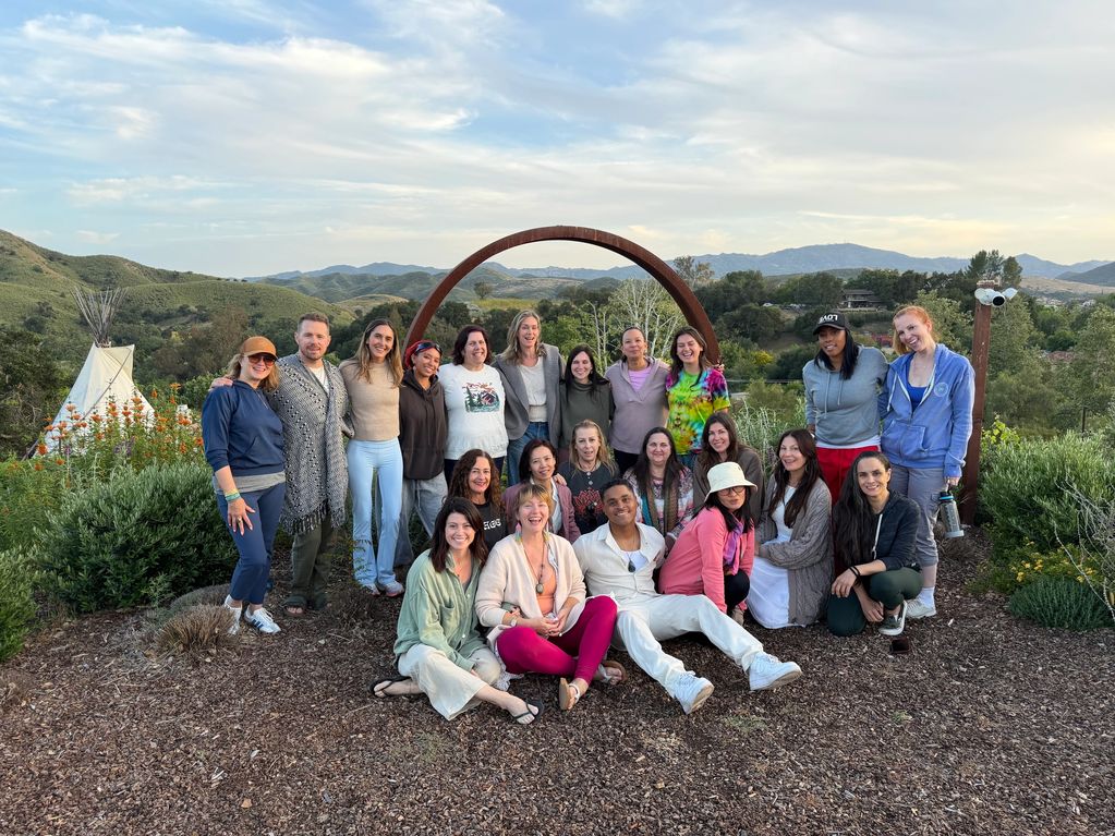 Group photo of 20 people outdoors with hills and trees in the background.