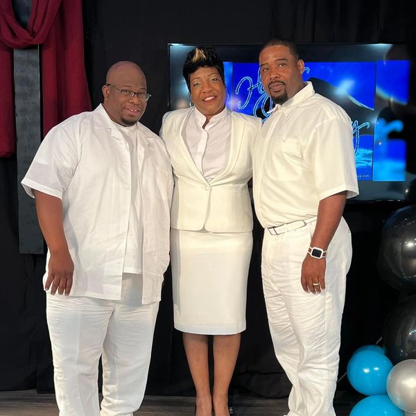 Three people dressed in white posing together indoors.