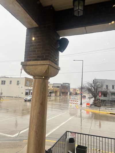 Rainy day on a quiet street corner with wet pavement and overcast sky.