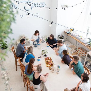 Group of people gathered around a large table in a bright, modern studio space.